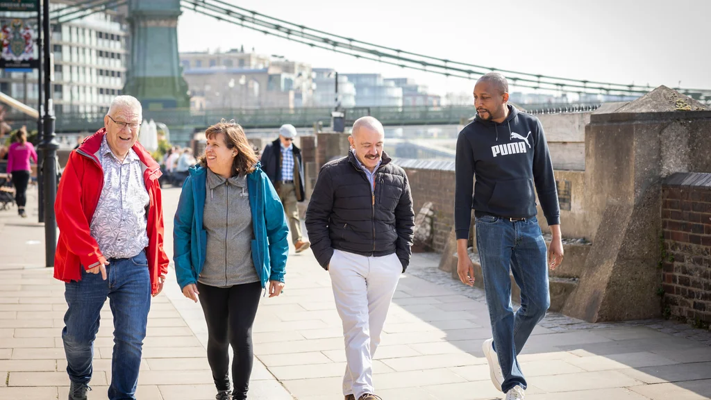 Four people walking outside on a bridge