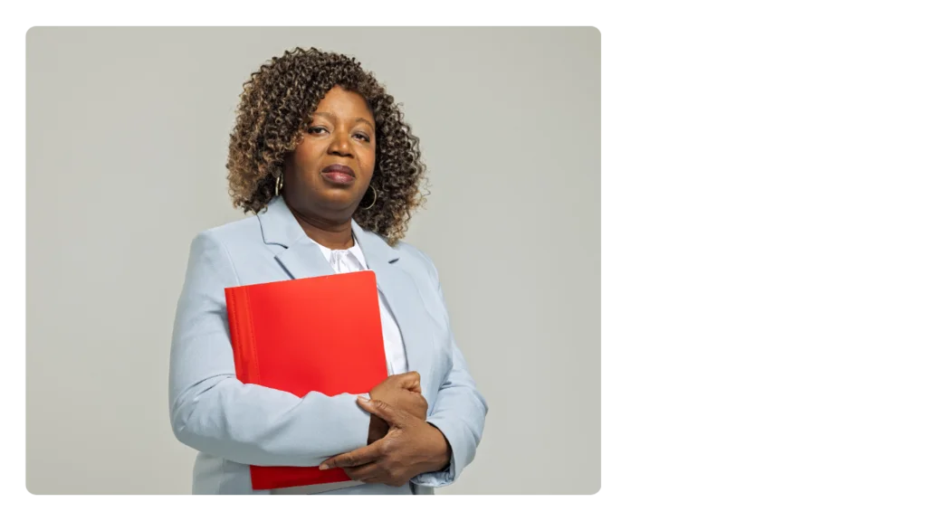 A woman wearing a suit and holding a red folder